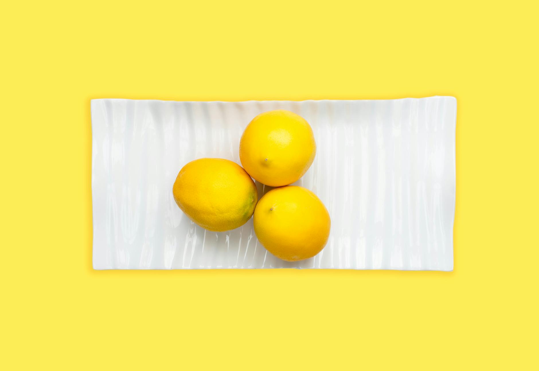 Blue vibrator surrounded by flowers and citrus slices on a bright yellow background