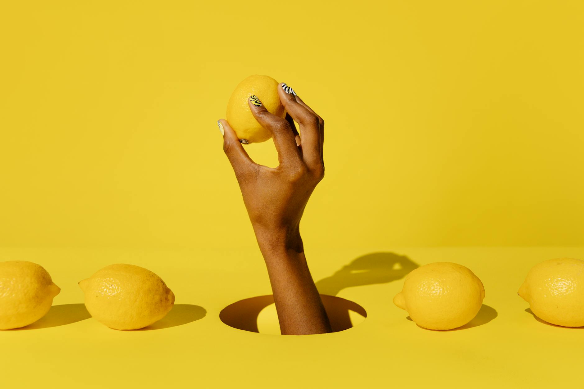 A lemon vibrator surrounded by flowers and citrus slices on a yellow background, symbolizing cycle-aware pleasure