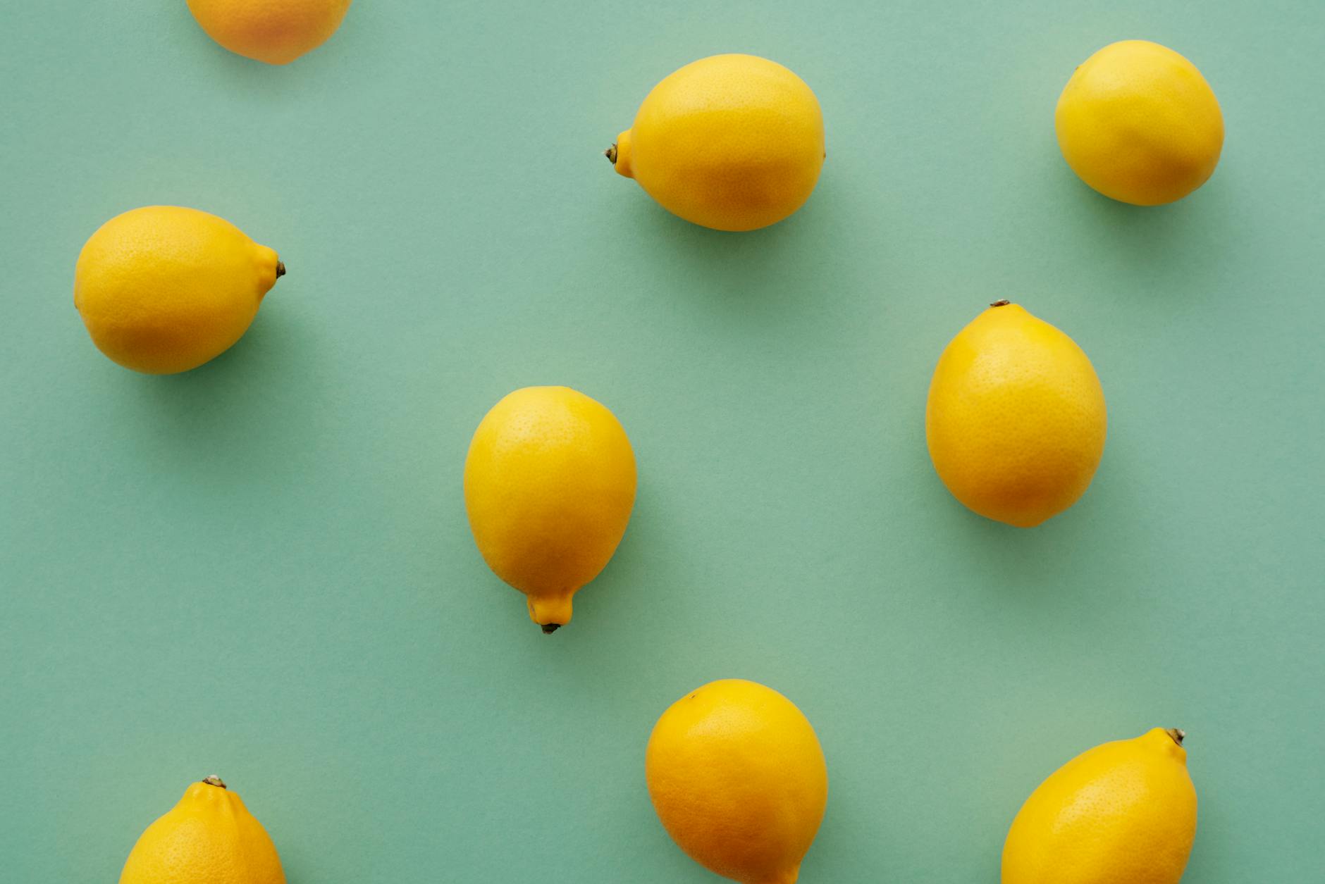 Bright yellow lemons arranged on a pastel green background, representing fresh lemon vibrators