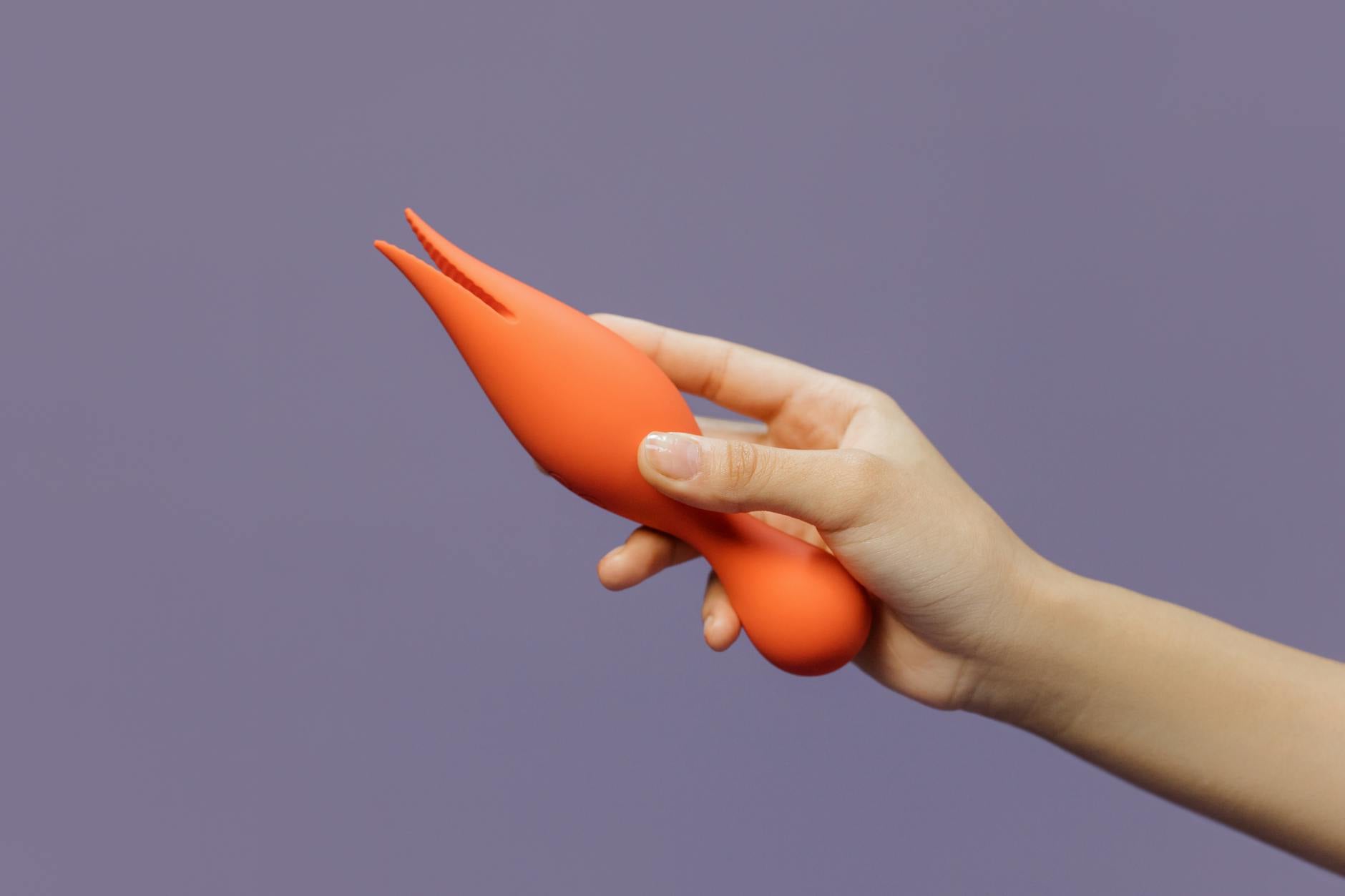 A hand holding a lemon vibrator against a minimalistic purple backdrop, representing gentle recovery and sensuality