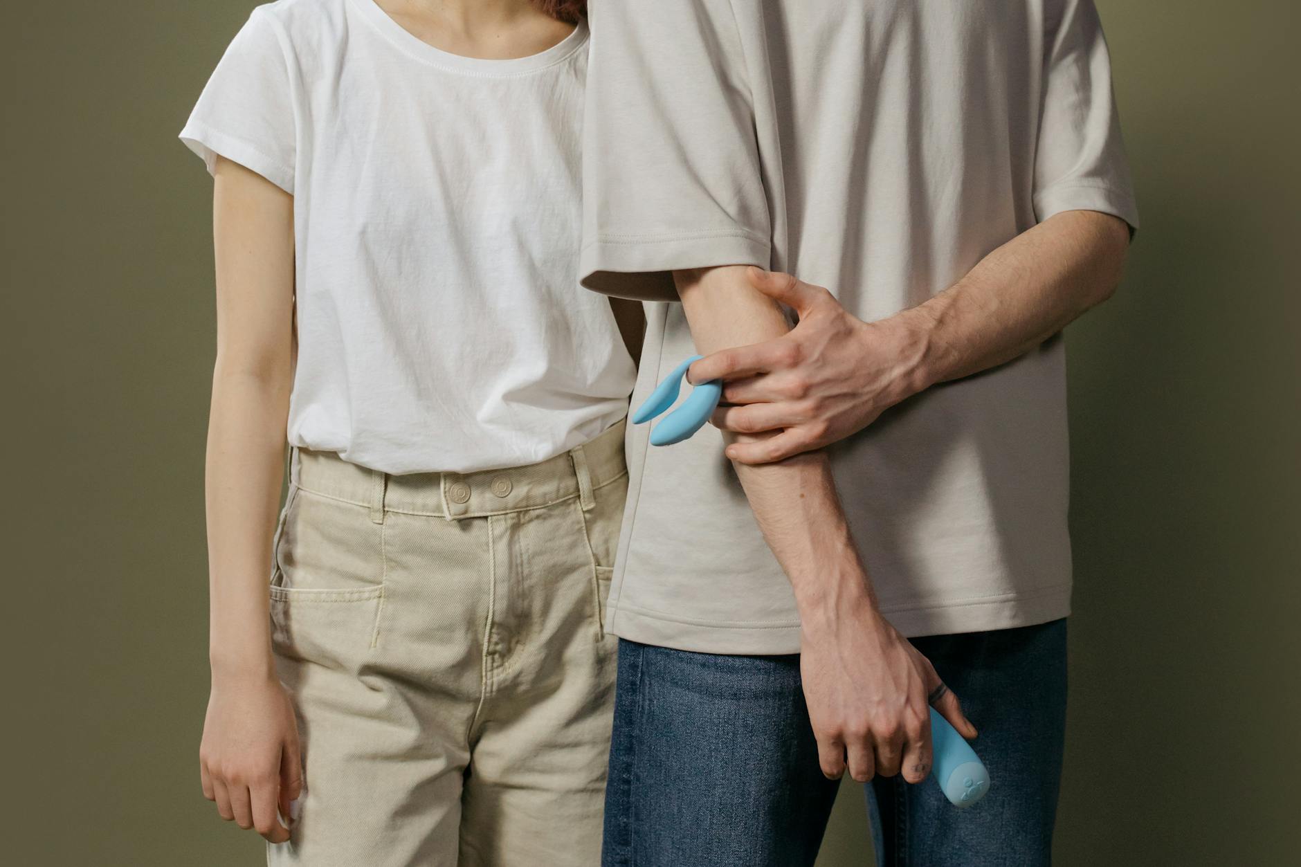 Close-up of a hand holding an orange vibrator against a minimalistic purple backdrop, showcasing modern sensuality and intimate wellness.